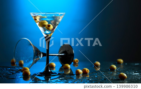 Green olives and glass of martini on a black stone table. Green olives and glass of martini on a black stone table. 139986310