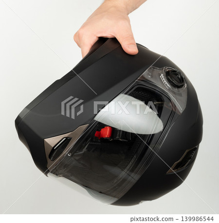 Holding a black motorcycle helmet with visor before wearing it Holding a black motorcycle helmet with visor before wearing it 139986544