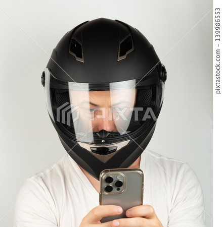 Man in black motorcycle helmet takes selfie with smartphone in hand Man in black motorcycle helmet takes selfie with smartphone in hand 139986553