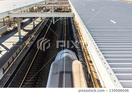 An aerial view of the Shinkansen's nose passing through the station platform and the tracks. 139986696
