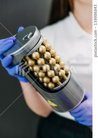 Young woman cosmetologist holding a professional hardware massage device used for body treatments. Aesthetic medicine, beauty procedures, slimming, toning, cellulite reduction, and wellness concept 139986843