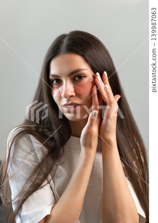 Vertical beauty portrait of young woman wearing hydrogel under-eye patches during skincare routine at home. Concept of self-care, healthy skin and modern facial treatment. Vertical beauty portrait of young woman wearing hydrogel under-eye patches during skincare routine at home. Concept of self-care, healthy skin and modern facial treatment. 139987063