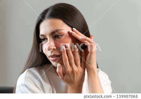 Young woman relaxing with hydrogel under-eye patches during daily skincare routine at home. Natural beauty portrait focused on self-care, healthy skin and modern cosmetic treatment. Young woman relaxing with hydrogel under-eye patches during daily skincare routine at home. Natural beauty portrait focused on self-care, healthy skin and modern cosmetic treatment. 139987068