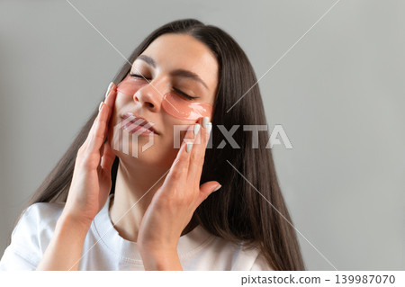 Young woman relaxing with hydrogel under-eye patches during daily skincare routine at home. Natural beauty portrait focused on self-care, healthy skin and modern cosmetic treatment. Young woman relaxing with hydrogel under-eye patches during daily skincare routine at home. Natural beauty portrait focused on self-care, healthy skin and modern cosmetic treatment. 139987070