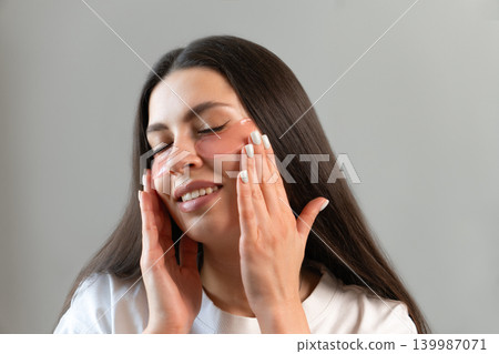 Young woman relaxing with hydrogel under-eye patches during daily skincare routine at home. Natural beauty portrait focused on self-care, healthy skin and modern cosmetic treatment. Young woman relaxing with hydrogel under-eye patches during daily skincare routine at home. Natural beauty portrait focused on self-care, healthy skin and modern cosmetic treatment. 139987071