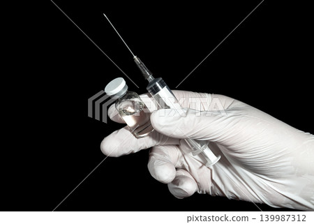 Medicine bottle and syringe in hand in latex glove Medicine bottle and syringe in hand in latex glove 139987312