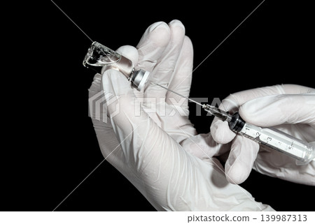 Medic's hands in a gloves with a syringe and a vial of vaccine Medic's hands in a gloves with a syringe and a vial of vaccine 139987313
