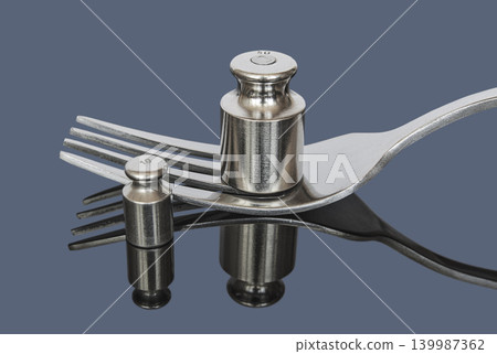 Metal weights for medical scales near fork on a dark background Metal weights for medical scales near fork on a dark background 139987362