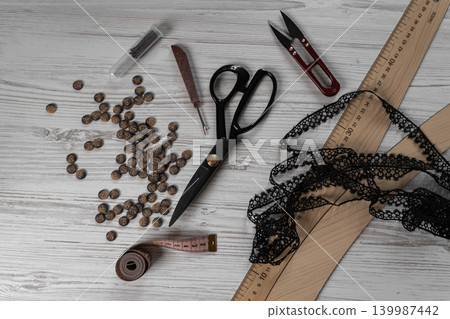 Collection of sewing tools and tailoring accessories including scissors, measuring tape, ruler, threads and buttons arranged on table. Concept of handmade craft, tailoring, fashion design and 139987442