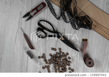 Collection of sewing tools and tailoring accessories including scissors, measuring tape, ruler, threads and buttons arranged on table. Concept of handmade craft, tailoring, fashion design and 139987443