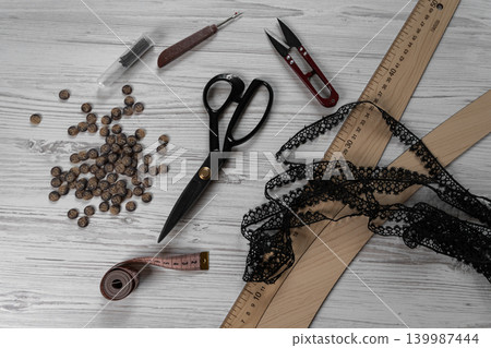 Collection of sewing tools and tailoring accessories including scissors, measuring tape, ruler, threads and buttons arranged on table. Concept of handmade craft, tailoring, fashion design and Collection of sewing tools and tailoring accessories including scissors, measuring tape, ruler, threads and buttons arranged on table. Concept of handmade craft, tailoring, fashion design and 139987444