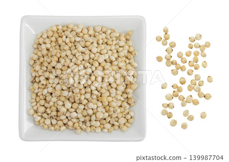 Sorghum seeds in ceramic bowl isolated on white background. Top view. Flat lay. Sorghum seeds in ceramic bowl isolated on white background. Top view. Flat lay. 139987704