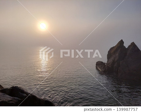 The sunrise over the Pacific Ocean shrouded in morning mist and the beautiful rocky shores of Fujinokawa Coast on the Sanriku coast in Miyako City, Iwate Prefecture. The sunrise over the Pacific Ocean shrouded in morning mist and the beautiful rocky shores of Fujinokawa Coast on the Sanriku coast in Miyako City, Iwate Prefecture. 139987757