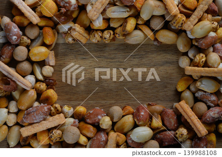 Colorful assortment of nuts and snacks creates a rustic frame on wooden table for a culinary treat Colorful assortment of nuts and snacks creates a rustic frame on wooden table for a culinary treat 139988108