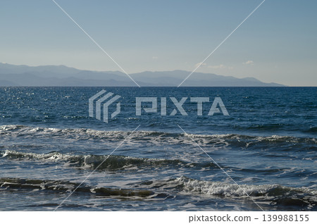 Soft waves caress the shore under a bright blue sky during a tranquil seaside Soft waves caress the shore under a bright blue sky during a tranquil seaside 139988155
