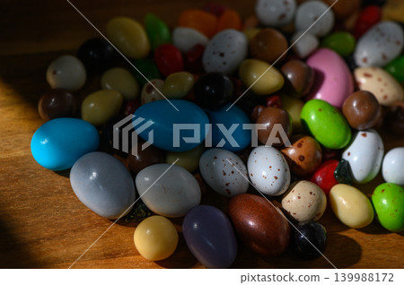 Colorful array of candy-coated chocolate eggs scattered on a wooden table Colorful array of candy-coated chocolate eggs scattered on a wooden table 139988172
