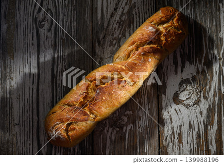 Freshly baked artisan bread resting rustic wooden table in warm afternoon light Freshly baked artisan bread resting rustic wooden table in warm afternoon light 139988196