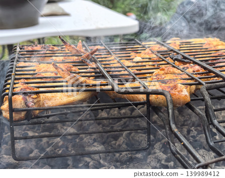 Delicious grilled chicken sizzling over charcoal in a vibrant outdoor setting Delicious grilled chicken sizzling over charcoal in a vibrant outdoor setting 139989412