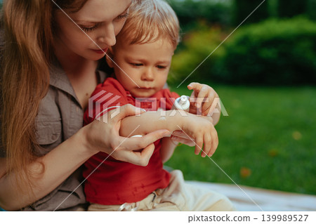 Mother puts cream on baby's hand in summer Mother puts cream on baby's hand in summer 139989527