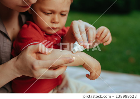 Mother puts cream on baby's hand in summer 139989528