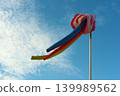 Colorful windsock or wind sleeve on blue sky background for showing wind strength and direction, copy space. Airport field or beach decoration. Traveling and swimming safety 139989562