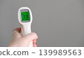 Hand holding infrared thermometer for temperature measure showing subfebrile 37 celsius degrees on green screen. Remote measurement of fever for children and public places, copy space. Flu season 139989563