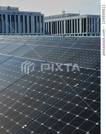 Rooftop solar panels cover modern building with office blocks in the background Rooftop solar panels cover modern building with office blocks in the background 139989811