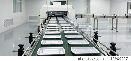 Automated production line with conveyor belt carrying empty trays in a cleanroom Automated production line with conveyor belt carrying empty trays in a cleanroom 139989937