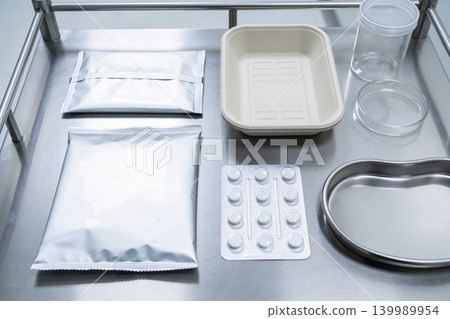 Medical supplies and packaging arranged on a sterile stainless steel tray 139989954