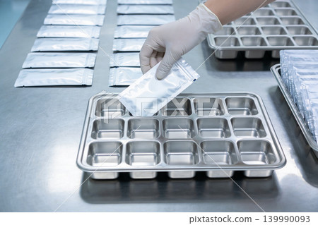 Gloved hand placing a sealed pouch into a compartmentalized tray for laboratory testing Gloved hand placing a sealed pouch into a compartmentalized tray for laboratory testing 139990093
