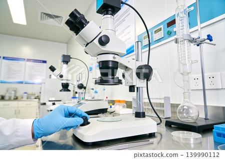 Scientist using a microscope in a modern laboratory setting for research Scientist using a microscope in a modern laboratory setting for research 139990112