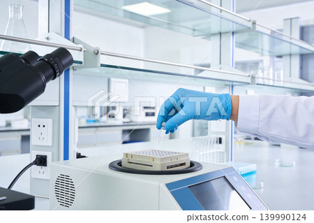 Scientist in blue gloves handles a sample tube in a modern laboratory setting 139990124