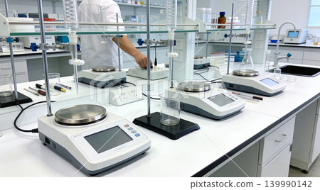 Modern laboratory equipment with digital scales and glassware on a clean white bench 139990142