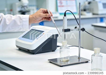 Scientist performing titration experiment with automated burette and digital display Scientist performing titration experiment with automated burette and digital display 139990145
