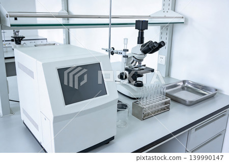 Modern laboratory equipment with microscope and testing devices on a clean white countertop Modern laboratory equipment with microscope and testing devices on a clean white countertop 139990147