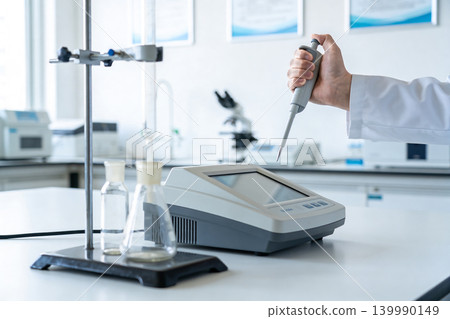 Scientist using a pipette in a modern laboratory with scientific equipment Scientist using a pipette in a modern laboratory with scientific equipment 139990149