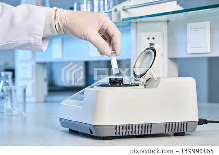 Scientist places sample tube into laboratory centrifuge for analysis Scientist places sample tube into laboratory centrifuge for analysis 139990165