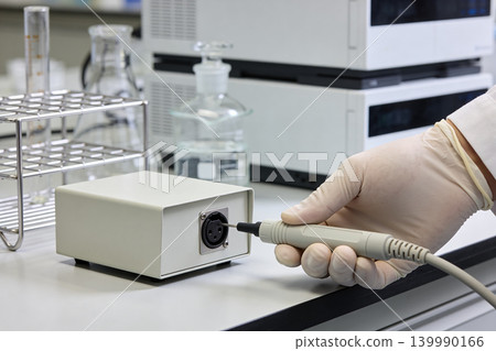 Scientist in sterile gloves connects probe to laboratory equipment for experiment 139990166