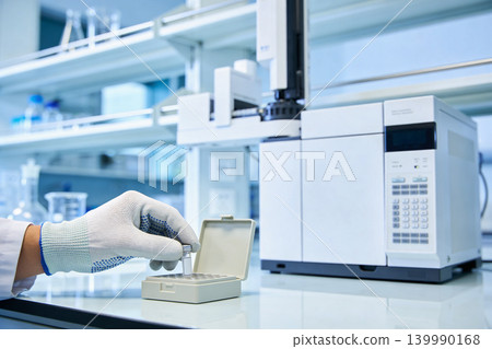 Scientist handling samples in a modern laboratory with advanced analytical equipment Scientist handling samples in a modern laboratory with advanced analytical equipment 139990168