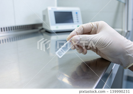 Scientist in sterile gloves holds a small transparent sample container in a laboratory Scientist in sterile gloves holds a small transparent sample container in a laboratory 139990231