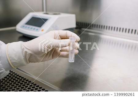 Scientist in sterile gloves holds a small sample tube in a laboratory setting Scientist in sterile gloves holds a small sample tube in a laboratory setting 139990261