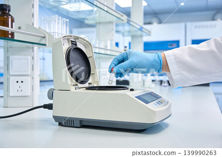 Scientist in blue gloves places vial into laboratory centrifuge for analysis Scientist in blue gloves places vial into laboratory centrifuge for analysis 139990263
