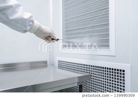 Scientist in sterile lab coat tests air quality with a probe emitting vapor Scientist in sterile lab coat tests air quality with a probe emitting vapor 139990309