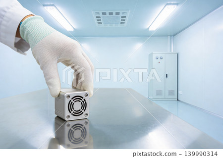 Scientist in cleanroom places small electronic device on sterile metal table Scientist in cleanroom places small electronic device on sterile metal table 139990314