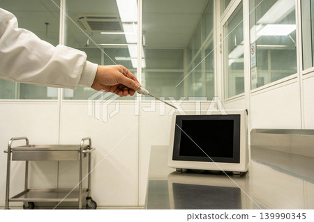 Scientist in lab coat uses thermometer probe near digital display in cleanroom Scientist in lab coat uses thermometer probe near digital display in cleanroom 139990345