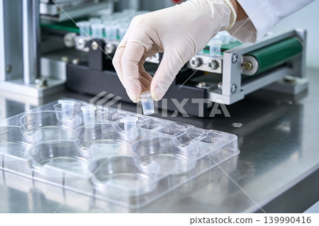 Laboratory technician handling sample vials during experiment setup 139990416