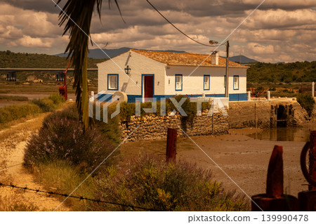 Charming white house with blue trim by a tidal estuary and distant bridge Charming white house with blue trim by a tidal estuary and distant bridge 139990478