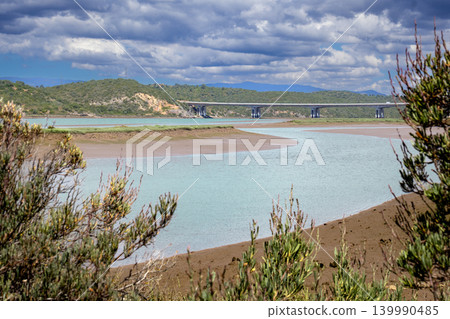Modern Highway bridge spans a tranquil river Arade with lush green hills under a cloudy sky Modern Highway bridge spans a tranquil river Arade with lush green hills under a cloudy sky 139990485