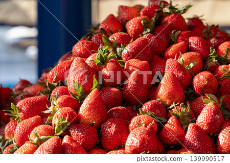Fresh strawberries illuminated by sunlight on a seasonal market stall. Selling strawberries at a farmers market. Freshly picked, beautiful strawberries on a street market counter. Strawberry season. 139990517