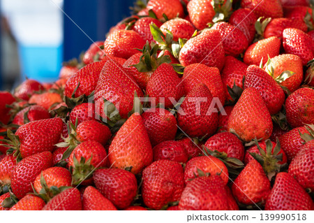 Fresh strawberries illuminated by sunlight on a seasonal market stall. Selling strawberries at a farmers market. Freshly picked, beautiful strawberries on a street market counter. Strawberry season. 139990518